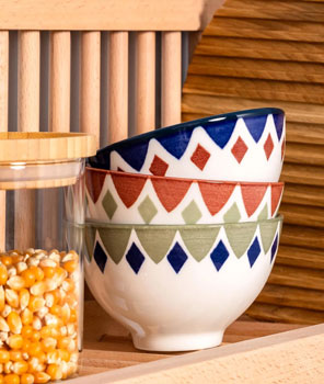 Two bowls rest on the top shelf of a plate rack. In the back ground is a wooden chopping board demonstrating that the plate rack storage shelf can be used to store a wide range of kitchenware items. 