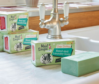 Several packs of our maid simple laundry soap sat one of top of the other, located by a sink. One bar of soap is out of the packaging showing the soap inside.